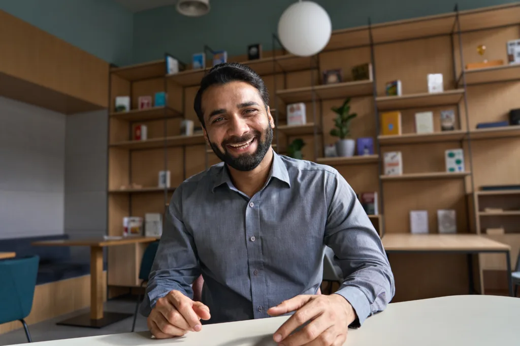 Optimizing Your Home Office for Video Conferencing. Image description: Happy indian business man, teacher talking to web cam on conference video call.